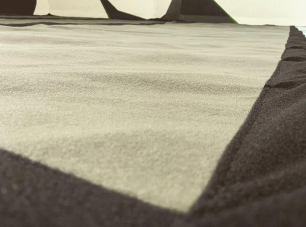 vista cercana del acabado de moqueta en una colchoneta instalada en la base de un rocódromo